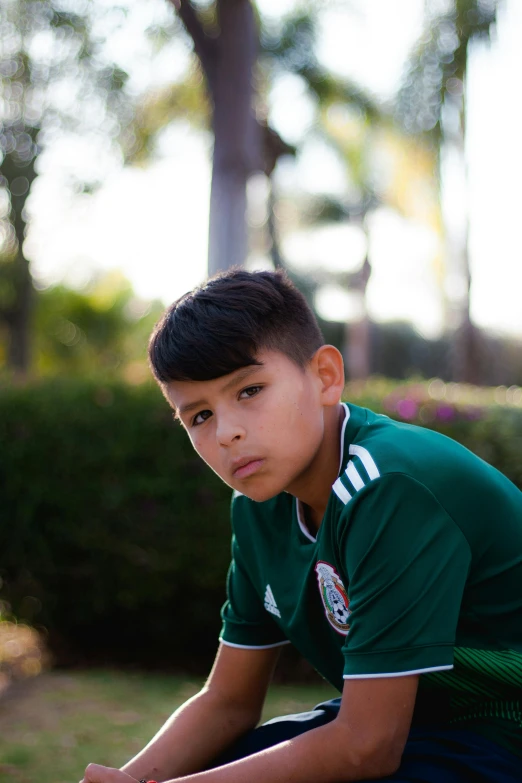 a small boy in green shirt sitting on grass