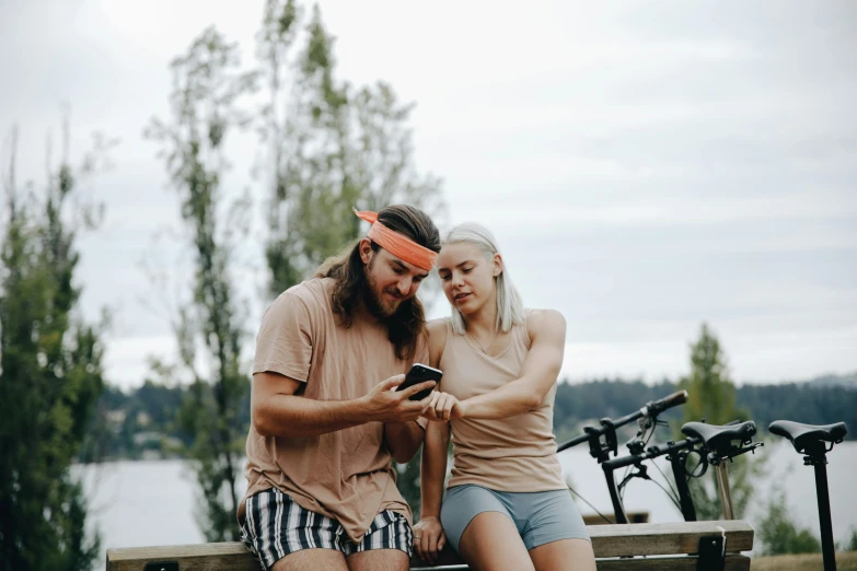 a couple on a bench looking at a cellphone