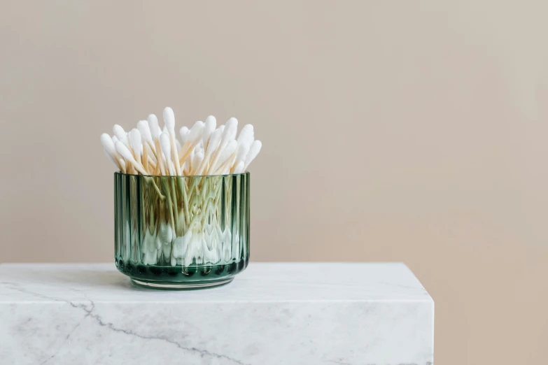 small green glass vase with lots of cotton tips