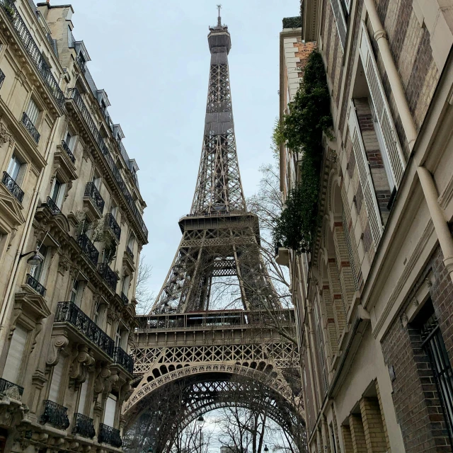 looking up at the eiffel tower from between two buildings