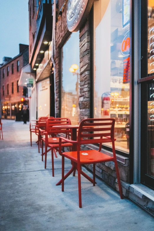 some red chairs are sitting outside on a sidewalk