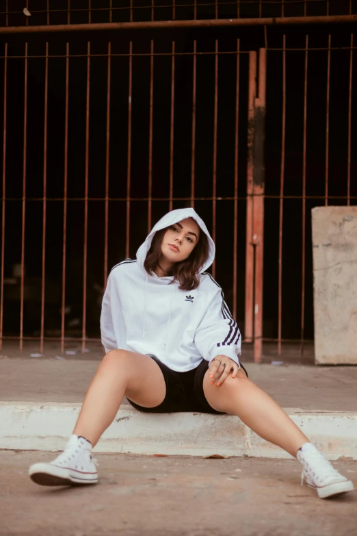 a woman in white hoodie sitting on steps with hand on hips