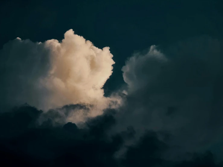 a picture of a very cloudy sky with the moon in the background