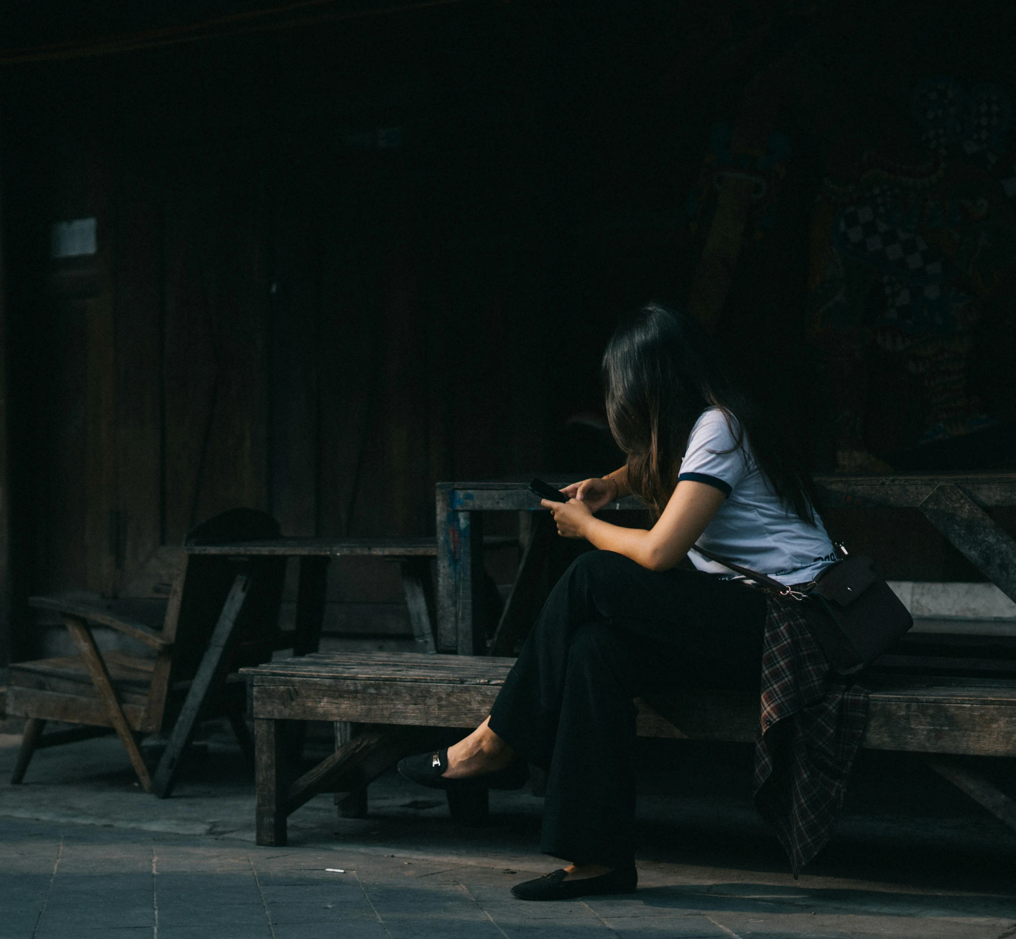 a woman is sitting on a wooden bench