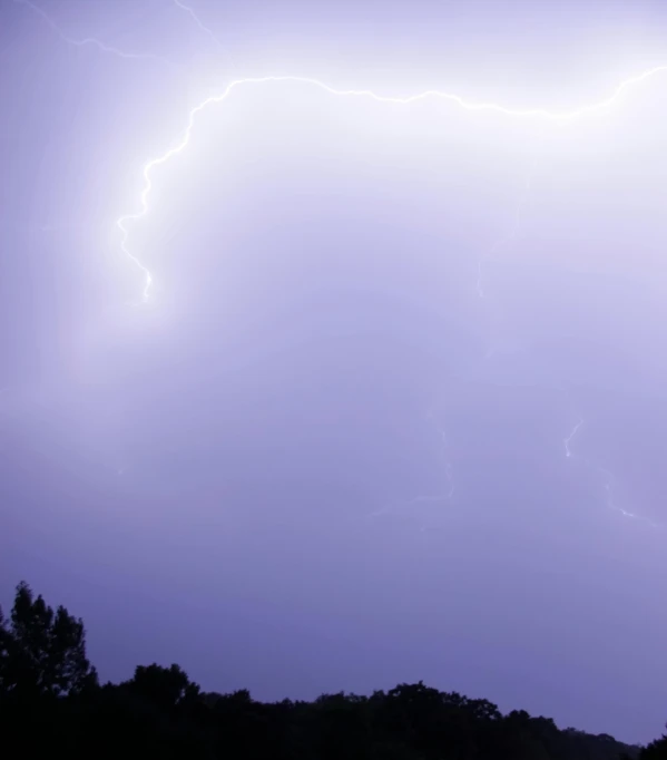 a dark sky with lightning hitting some trees