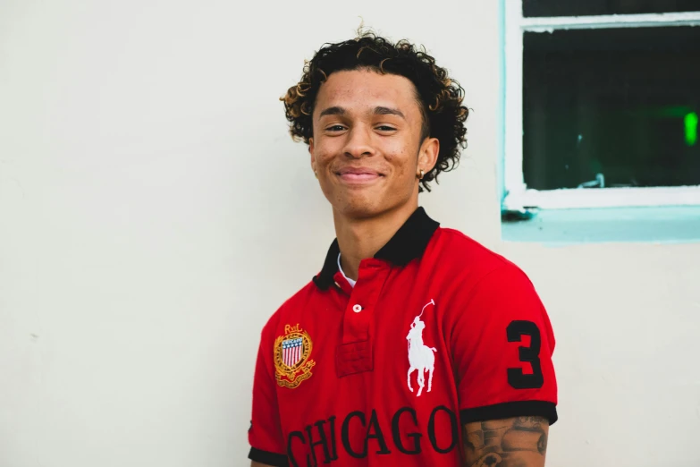 a young man posing in a polo shirt with a tattoo