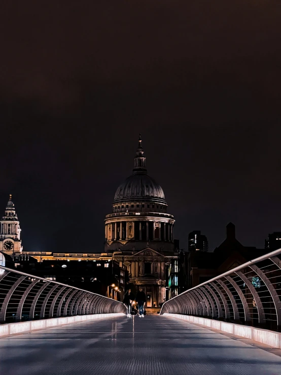 an illuminated bridge in front of large city buildings