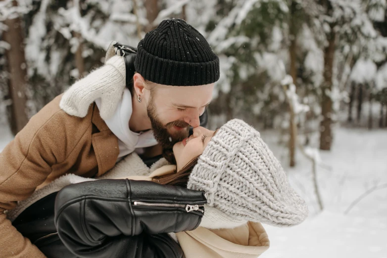 a man kissing his lady while he's covered in snow