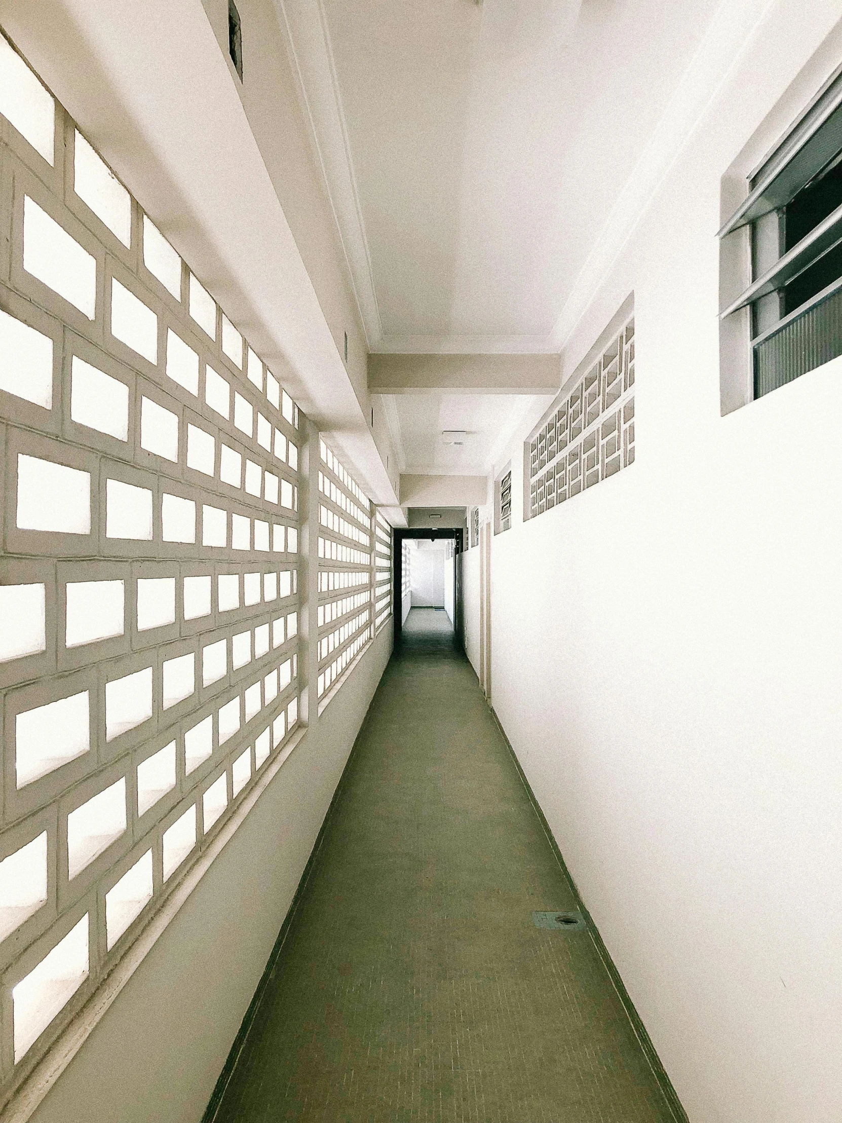 a long hallway has an empty ceiling and several windows