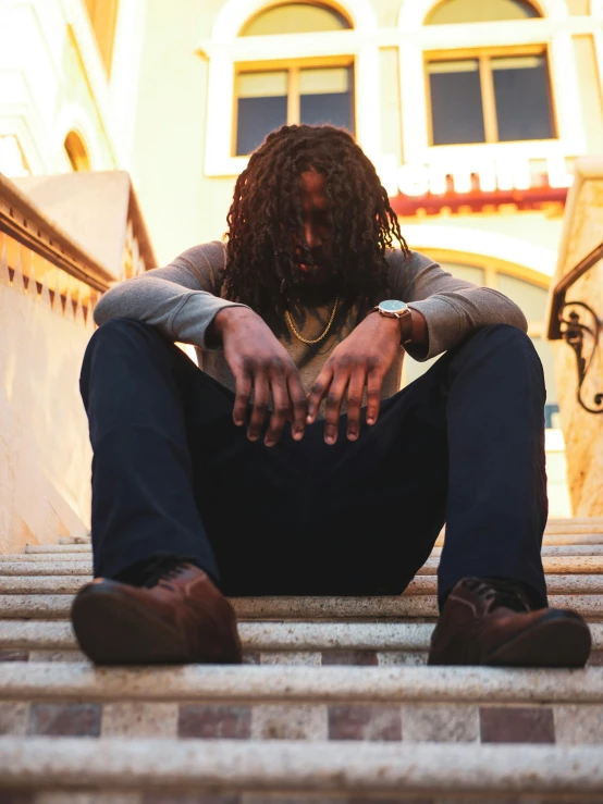 a man sitting on top of steps with his hands on his knees