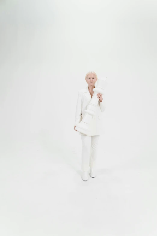 a woman in white suit and heels stands in the white room