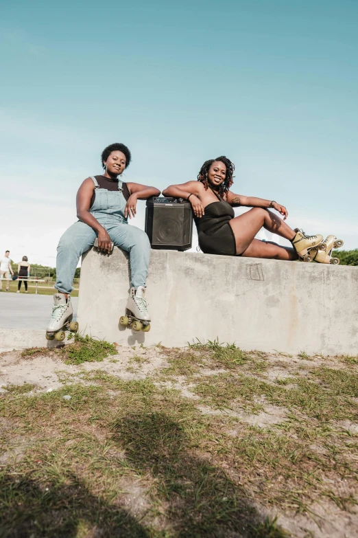 two young women sit on a wall with their arms around each other