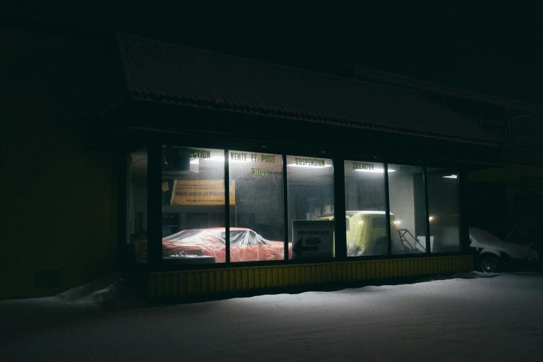 a car sits parked in a dark space outside a car showroom