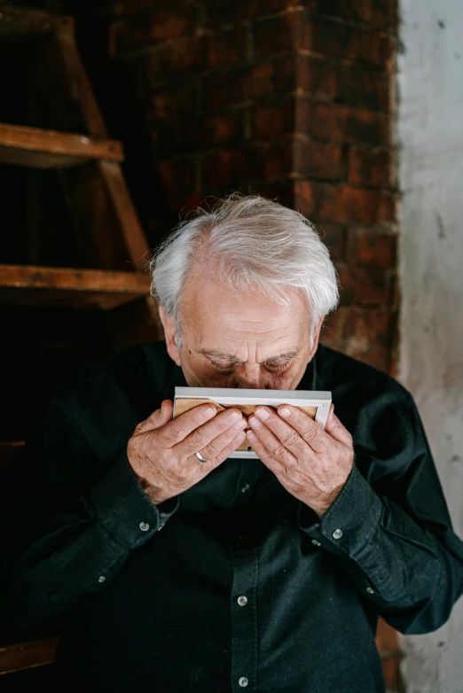 a man covers his mouth while holding soing in front of him