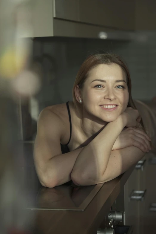 a woman smiling at the camera leaning on a counter