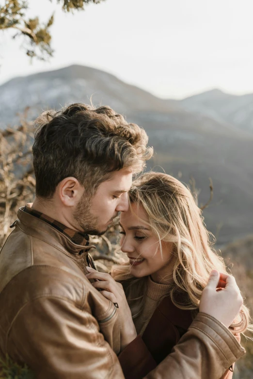 a man and woman are posing in the mountains