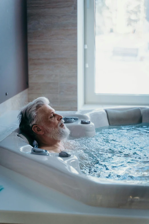 a man laying in a  tub while looking out the window