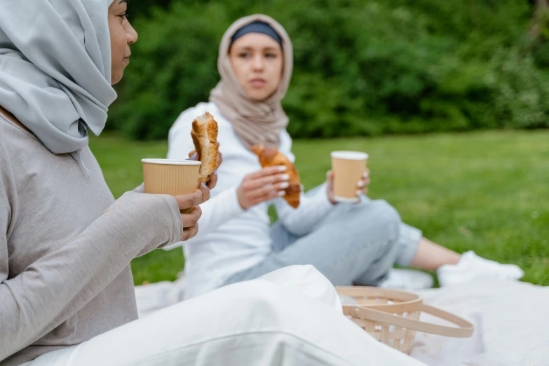 a couple of women sitting on top of a blanket