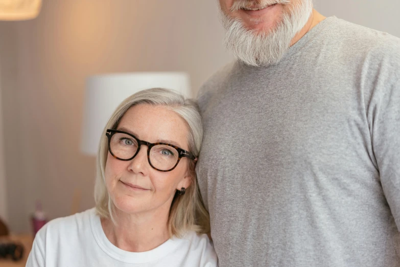 an older man with glasses hugging an old woman