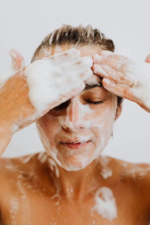 a young woman with her hands up in the air as she washes her face