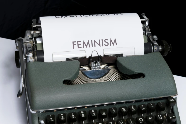 a close up of a typewriter with a piece of paper that says feminism