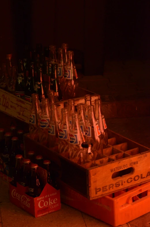 several bottles sit in an old crate, and one case holds several empty cokes