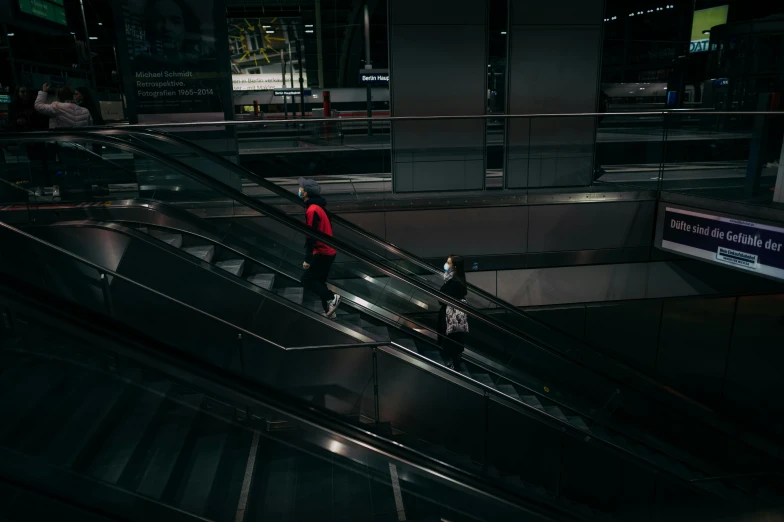 two people on an escalator near the luggage claim area