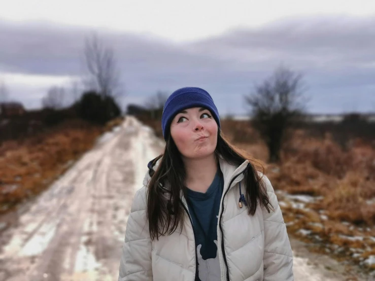 a young woman is standing on the snow covered road