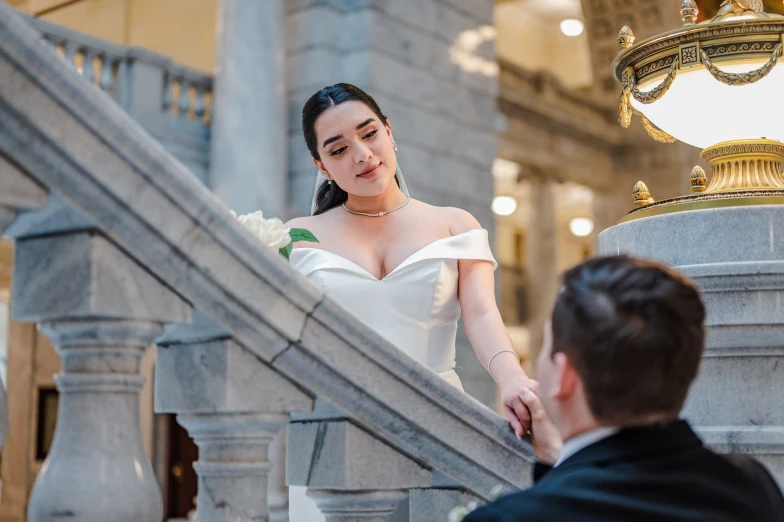 a close up of a woman wearing a white dress standing on the steps with a man