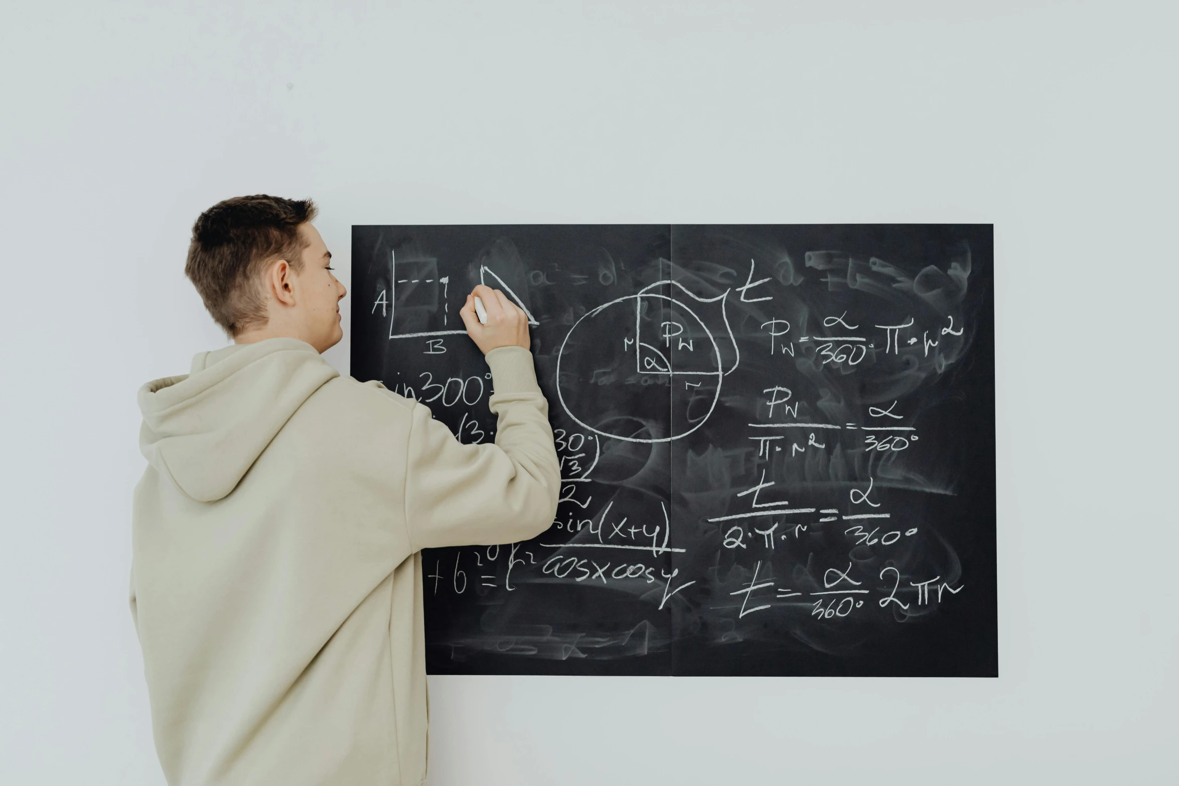 man writing on chalkboard with writing all over it