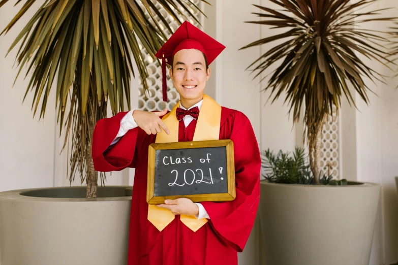 a man in a graduation cap and gown holding a sign