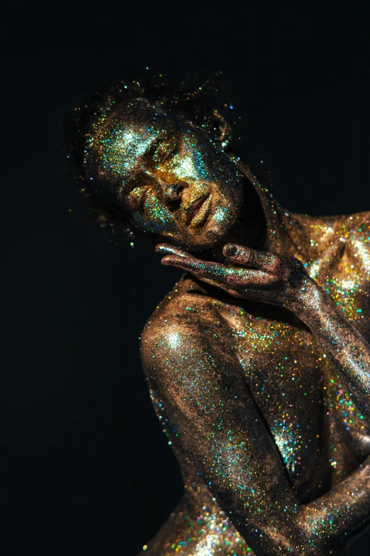 a woman covered in glitter on a dark background
