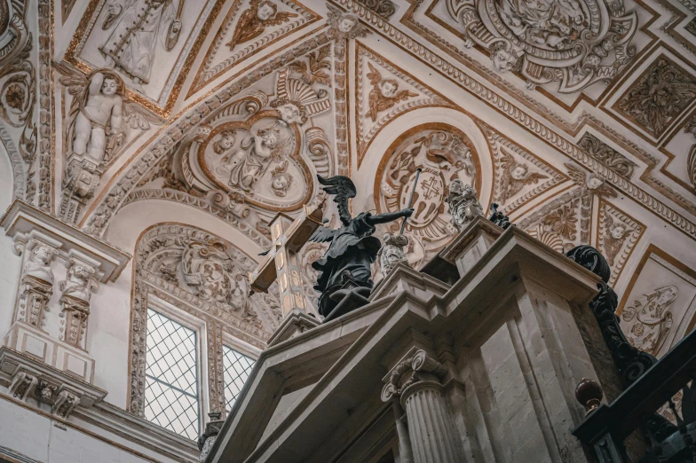 looking up at a clock tower with several statues on top