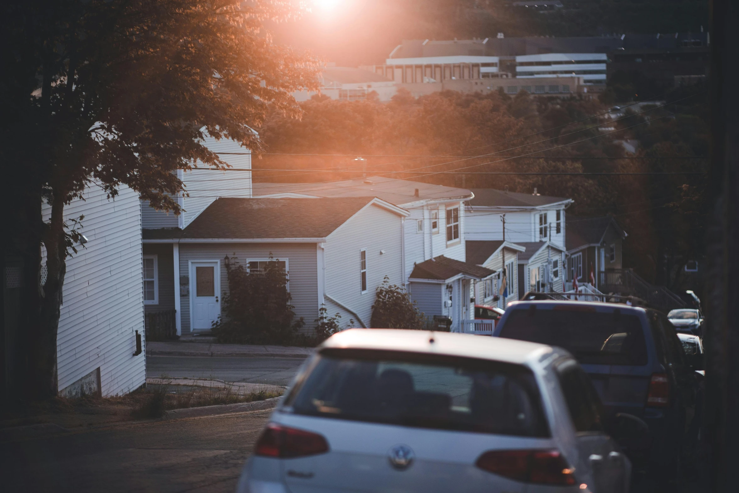 cars parked along the side of a road next to white houses