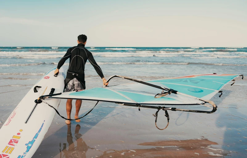 a man in a wetsuit is holding a surfboard near the water