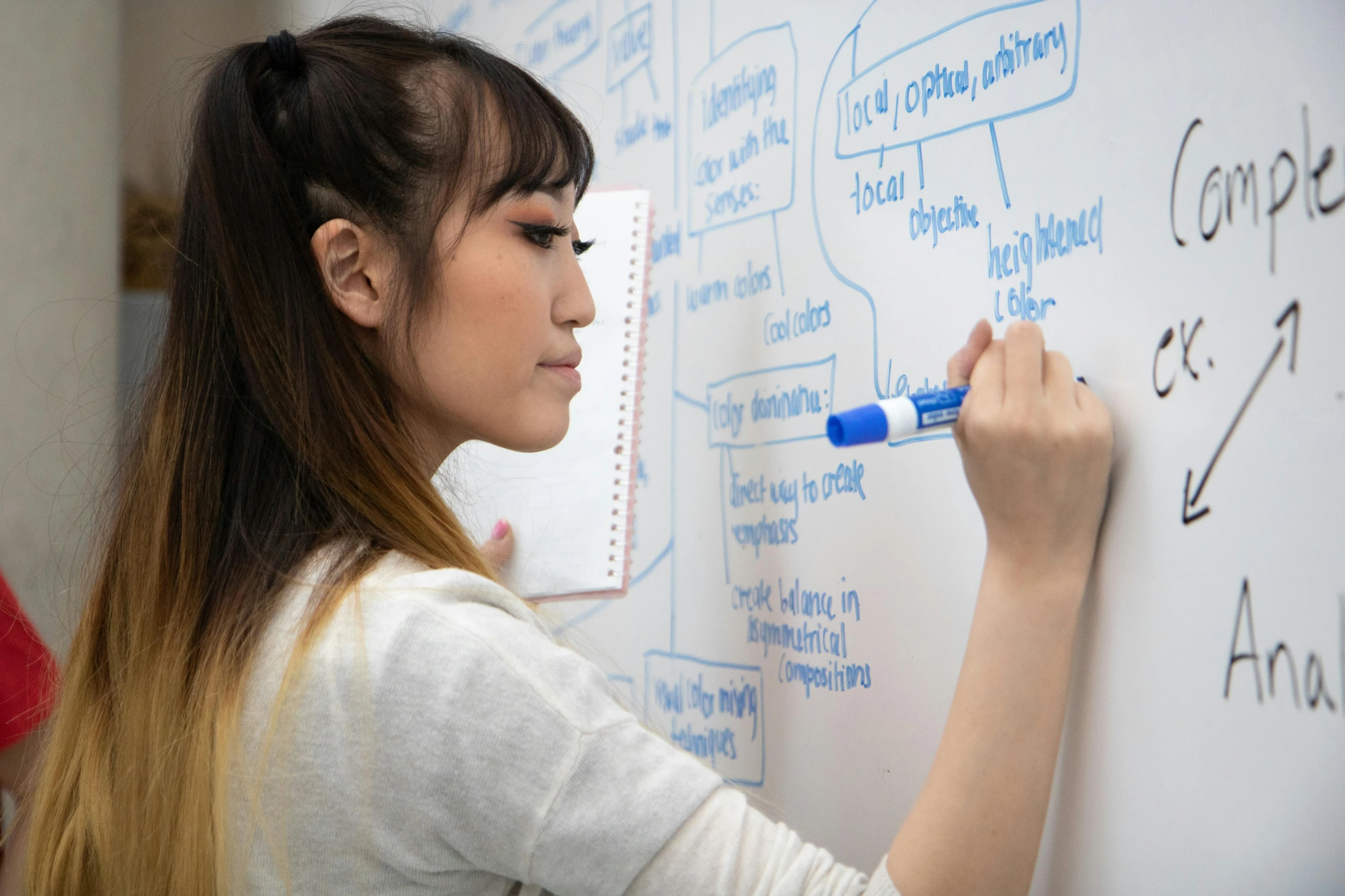 a female student writes on the whiteboard with marker