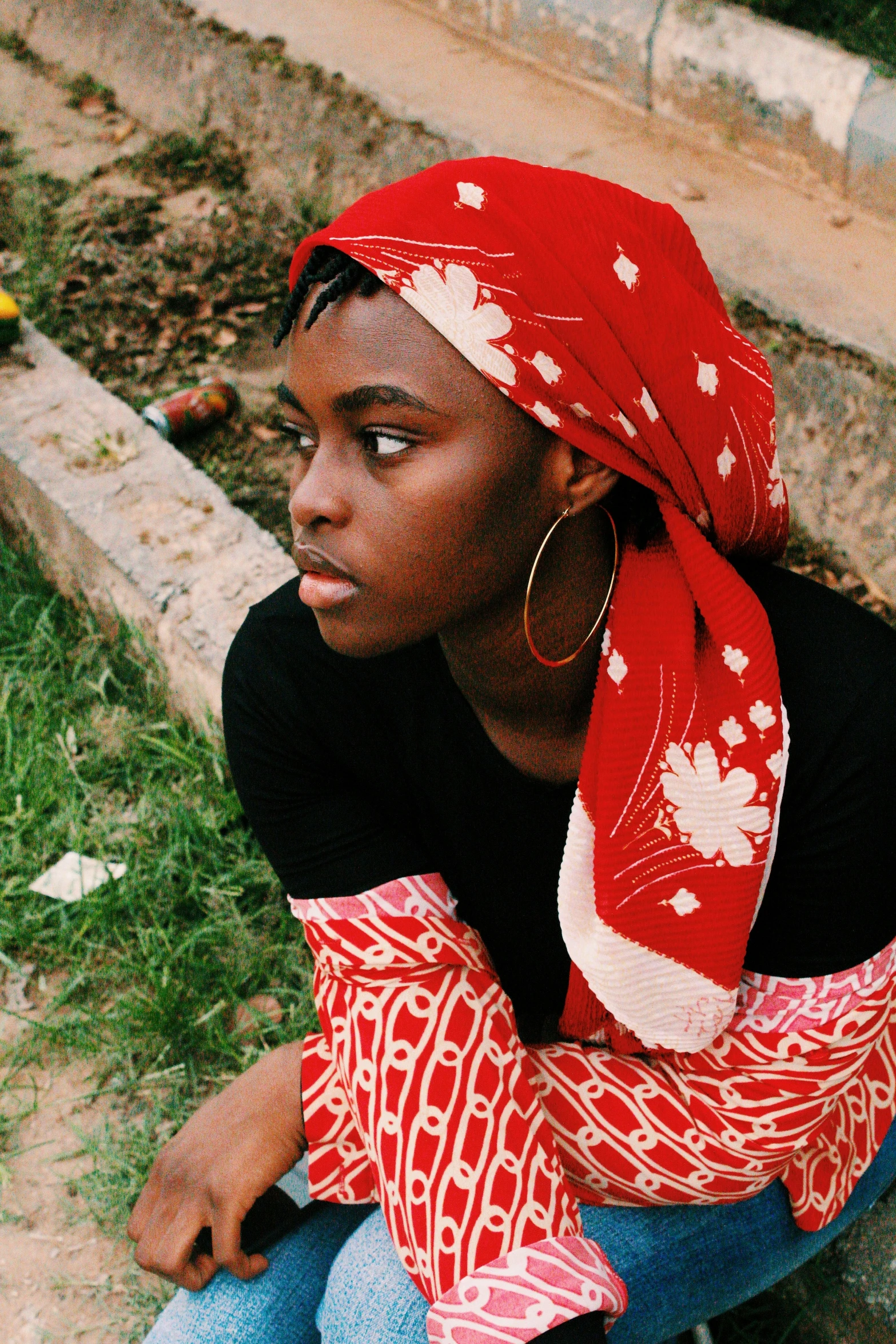 woman in red head wrap crouching with large earrings