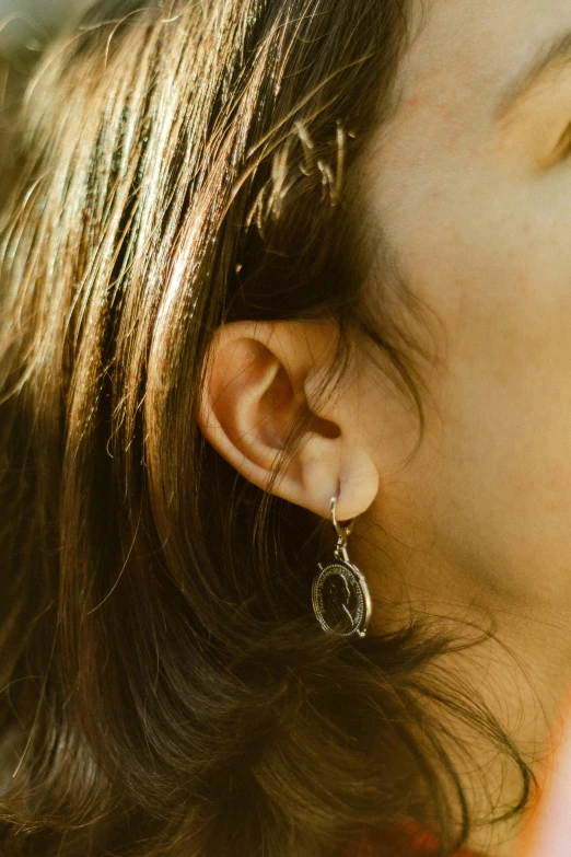 a young woman in earrings leans her head up to look down at the ground