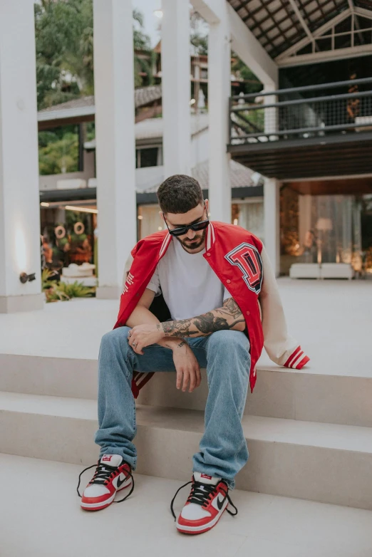 a man with tattoos sitting on a set of stairs