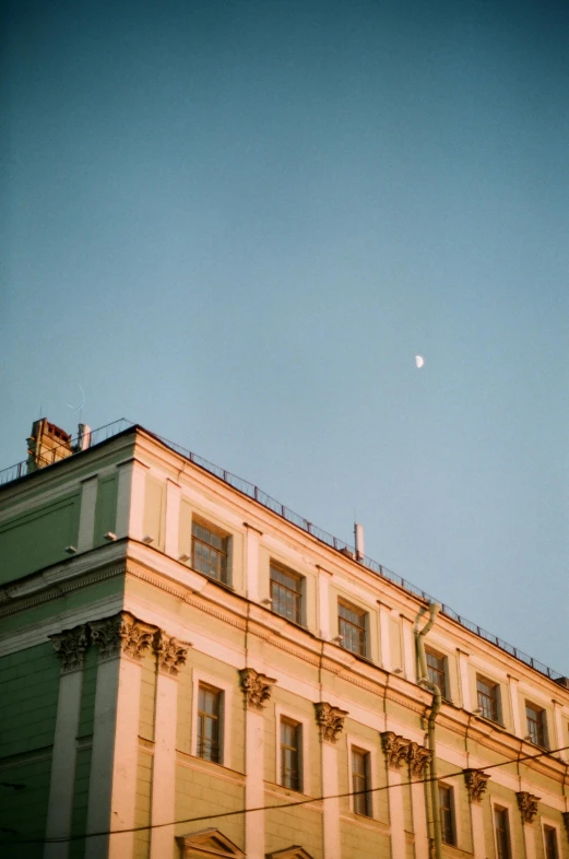 a building with several windows and the moon visible in the sky