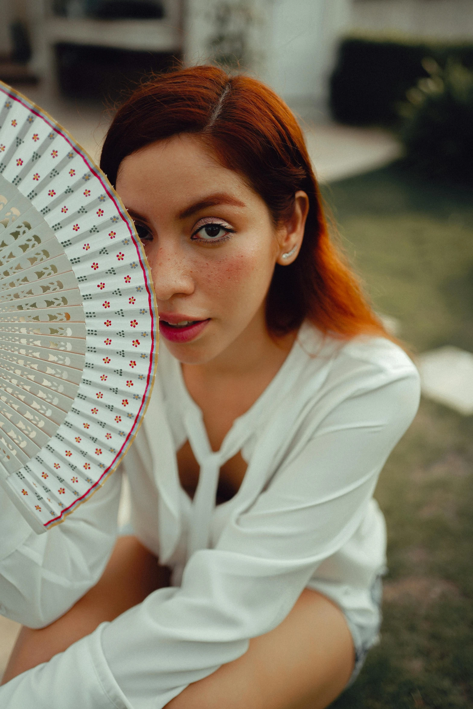 a woman with an orange hair posing while holding a white umbrella