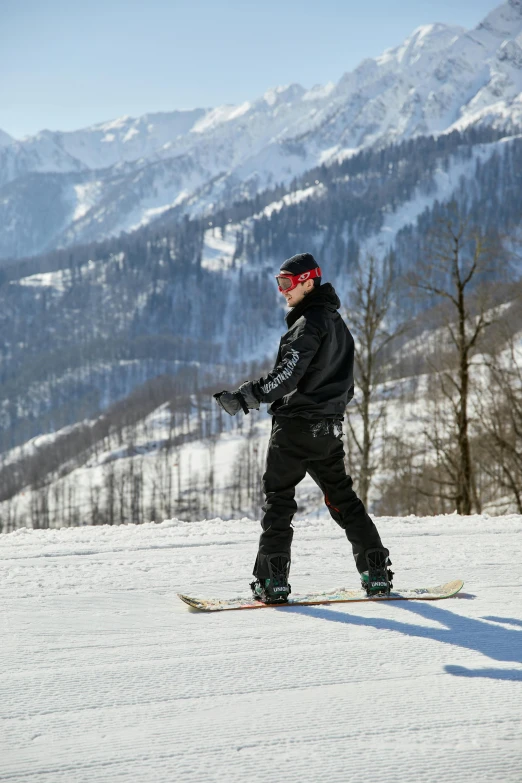 a man is standing on a snowboard on the slopes