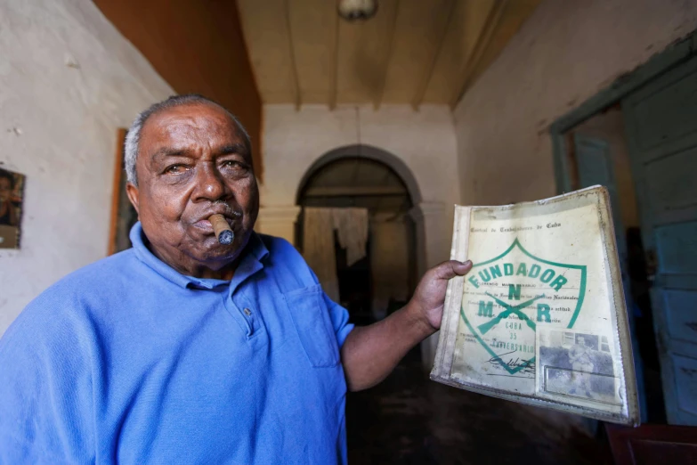 an old man standing in a hallway and smoking a cigar