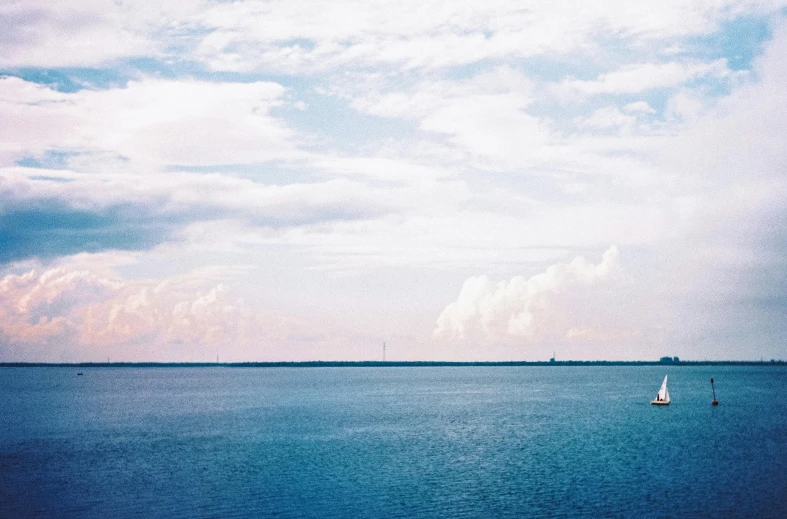 a lone boat is out in the ocean on a cloudy day