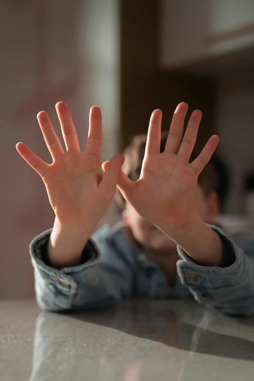 a person sitting at a table with their hands raised out