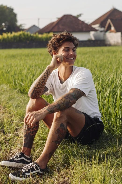 a man sitting in the middle of a green field