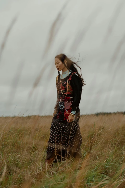 the girl is walking through tall grass in the field