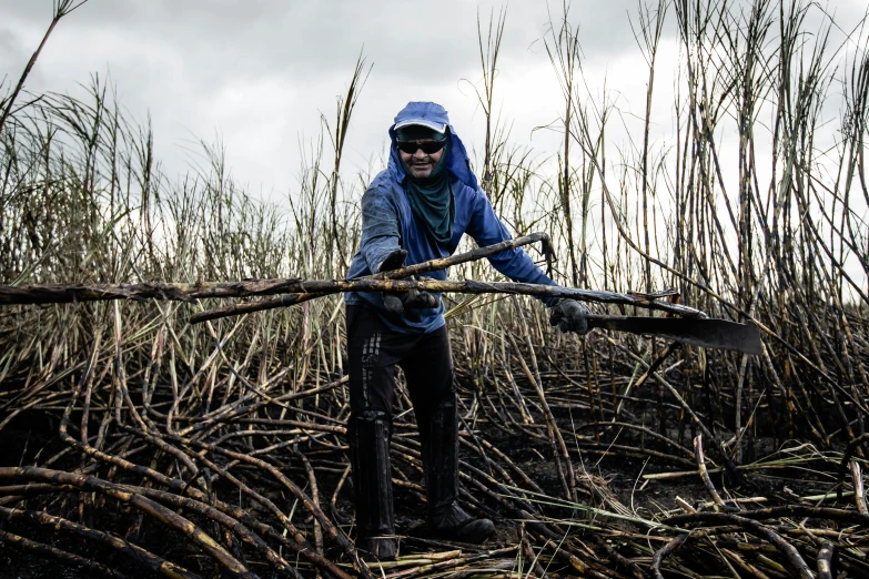 a person standing in a tall grass field holding a large axe