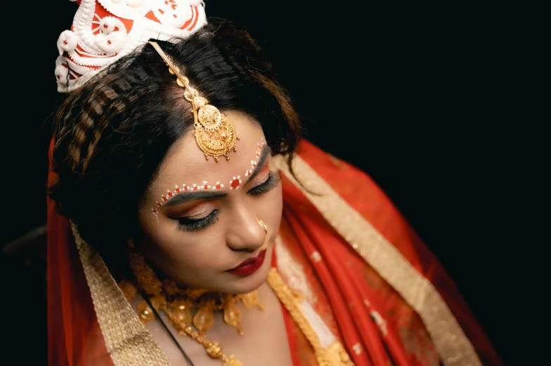 the bride is wearing a red and white outfit with gold jewelry