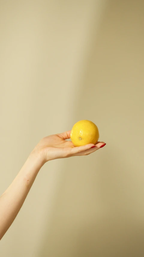 a woman holding an orange with a yellow top on her right hand